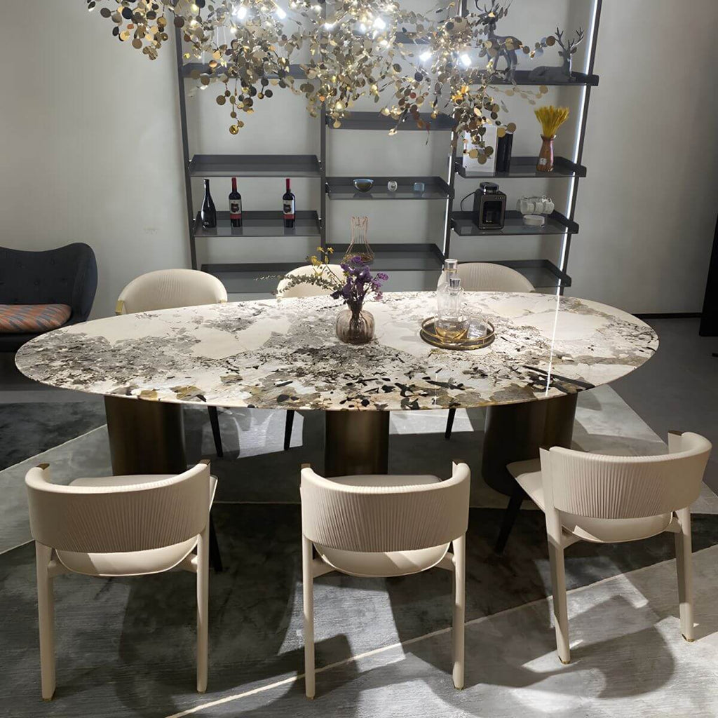 Oval marble dining table with white top and three gold steel legs