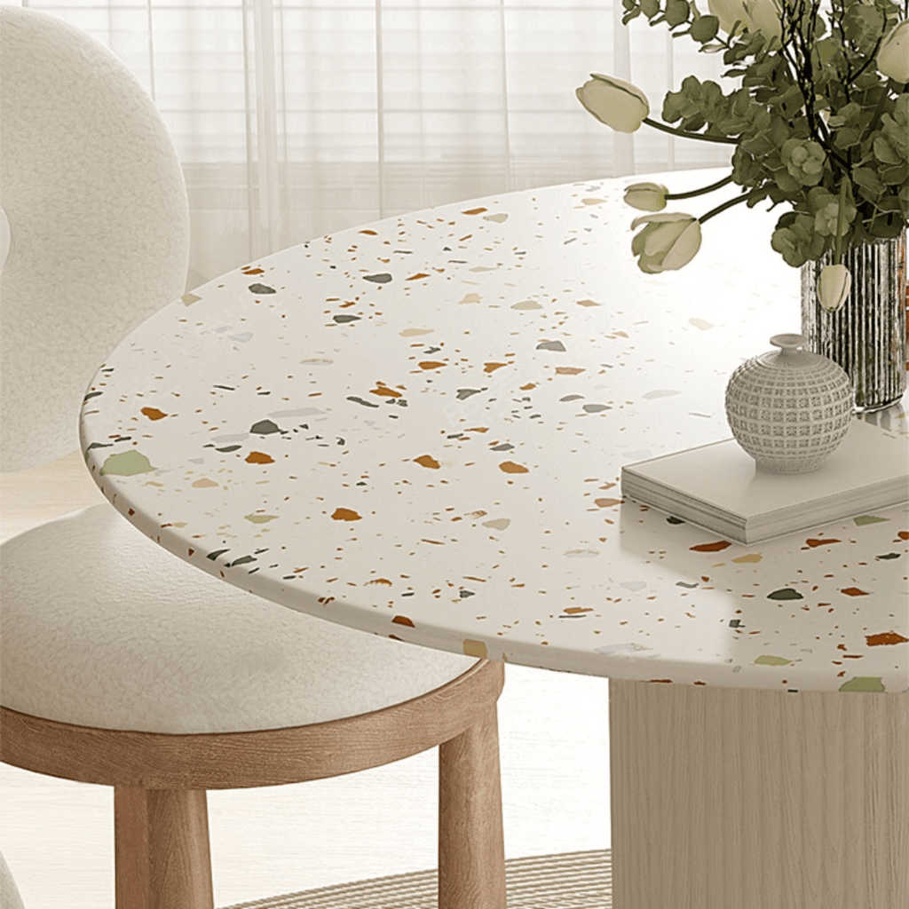 Round terrazzo dining table with soft wool upholstered chairs for a trendy home setup