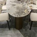 Oval marble dining table with white top and three gold steel legs