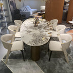 Oval marble dining table with white top and three gold steel legs