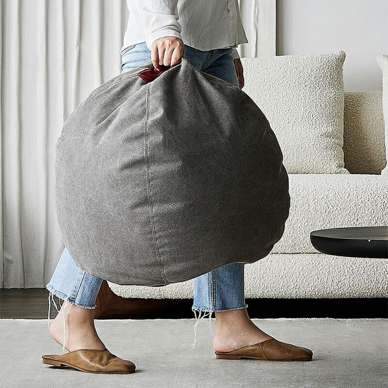 Stylish round gray pouf on hardwood floor