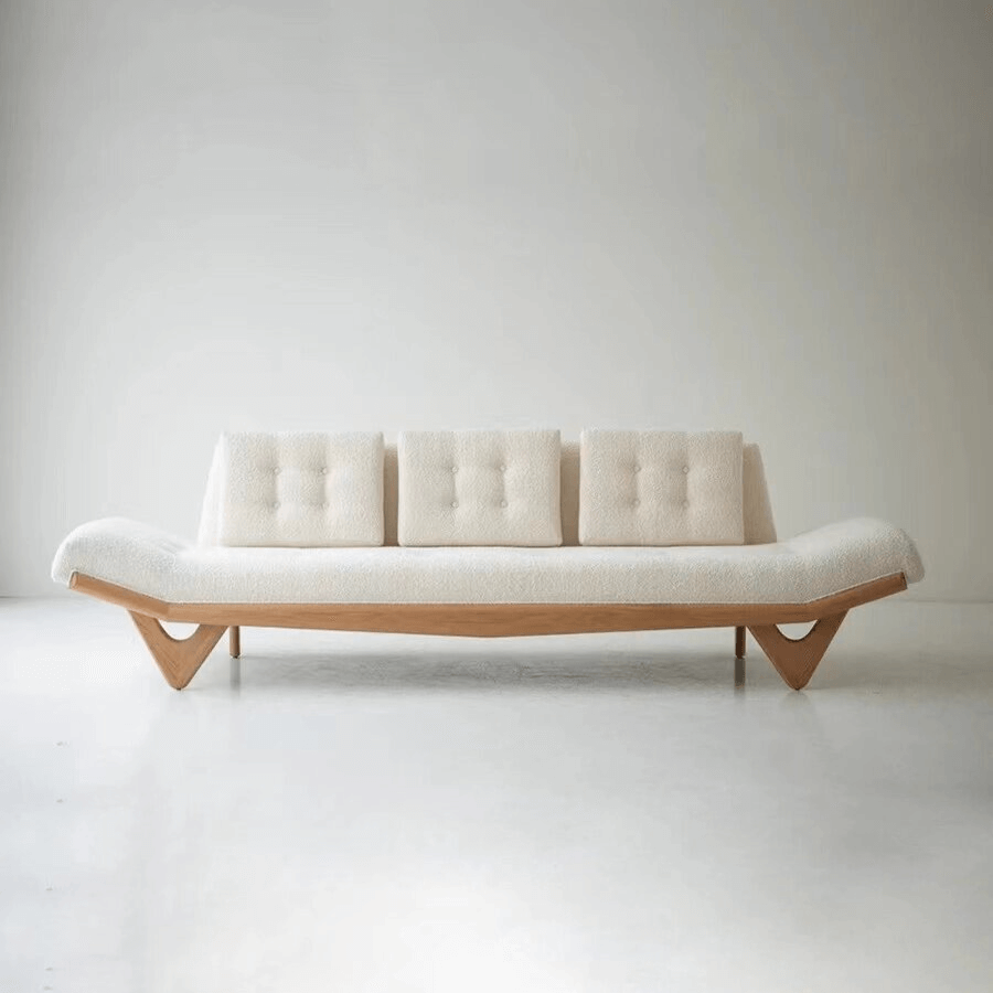 An Adrian Pearsall style boucle sofa in cream with a curved solid wood base, showcasing a modern and elegant design.