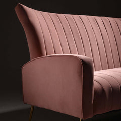 Pink velvet upholstered sofa with channel tufted design and wingback chair style