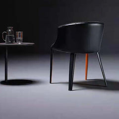 Contemporary upholstered saddle chair in black and orange with sleek metal legs for dining room